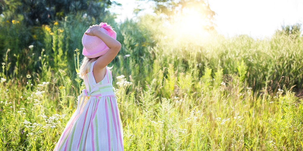 girl in field with bright sun